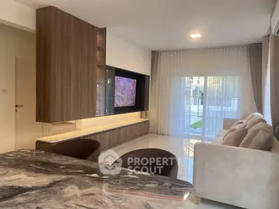 Modern living room with sleek furniture and large TV, featuring elegant marble table and cozy seating.