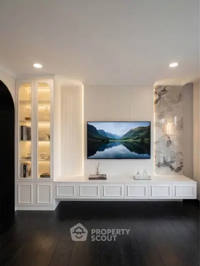 Elegant living room with built-in shelving and mounted TV, featuring modern design and ambient lighting.