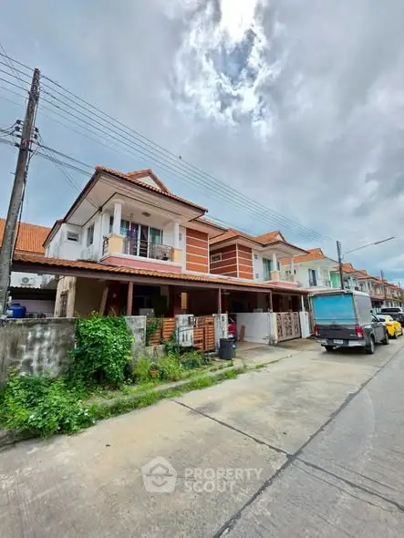 Charming suburban row houses with red-tiled roofs and lush greenery on a cloudy day.