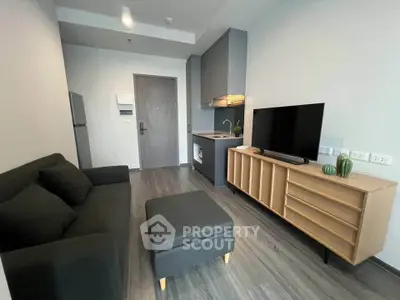 Modern living room with sleek furniture and compact kitchen in a stylish apartment.