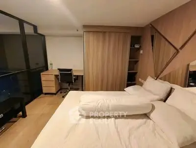Modern bedroom with wooden accents and a study desk, featuring a large window for natural light.