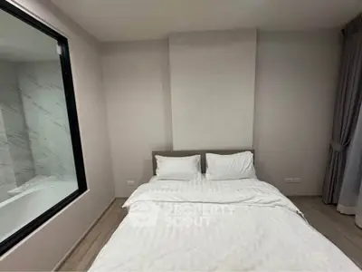 Modern bedroom with minimalist design and large window overlooking a stylish bathroom.