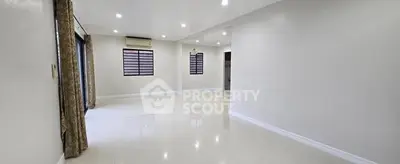 Spacious open-plan living room with elegant tile flooring and ample natural light.