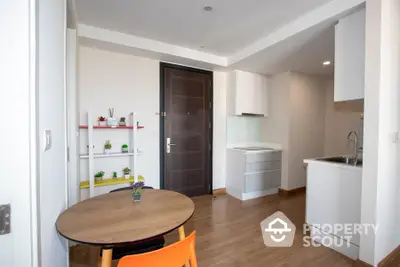 Modern apartment interior with compact kitchen and dining area, featuring sleek design and wooden flooring.