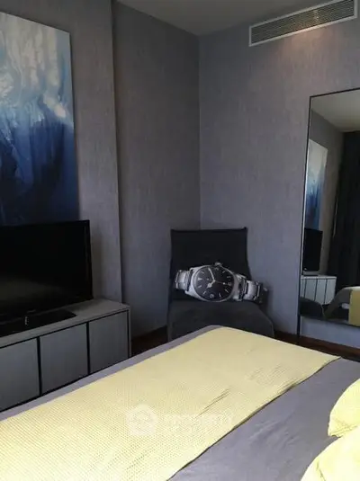 Modern bedroom with stylish decor and wall art, featuring a sleek TV setup and cozy ambiance.