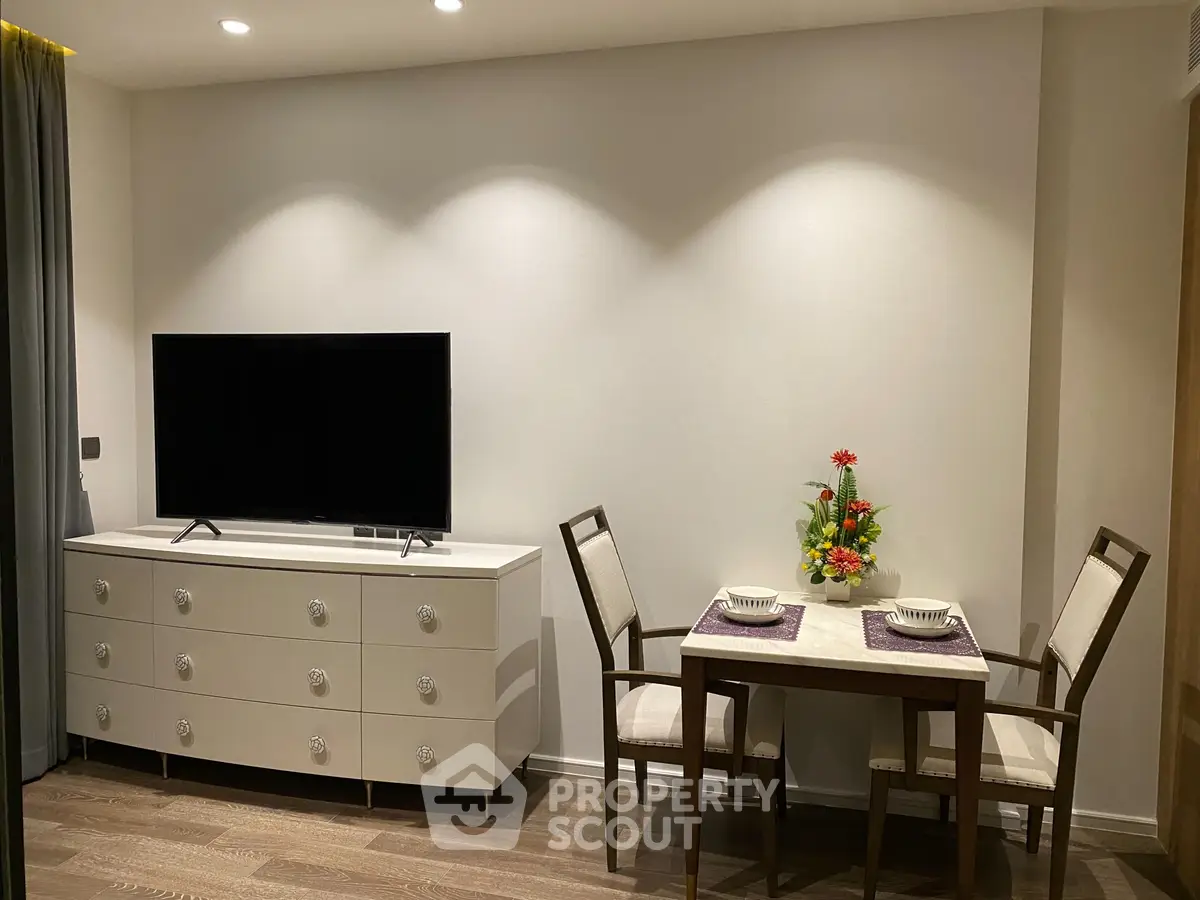 Modern living room with sleek TV setup and elegant dining area, perfect for cozy gatherings.