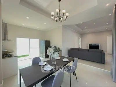 Modern open-plan living room and kitchen with elegant dining area and stylish chandelier.