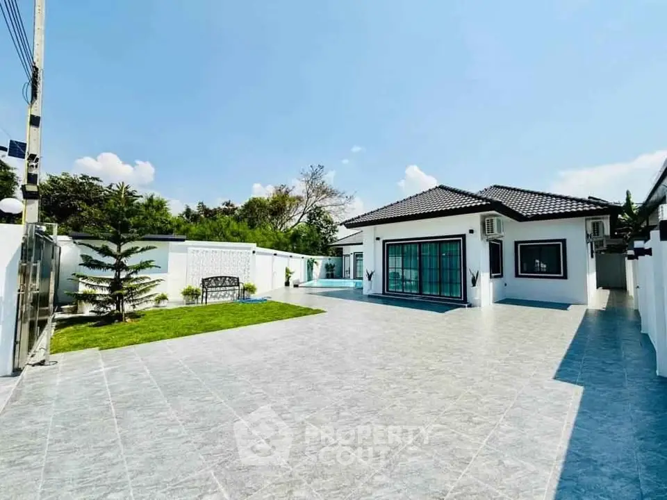 Spacious modern home with large tiled courtyard and lush greenery, perfect for outdoor living.