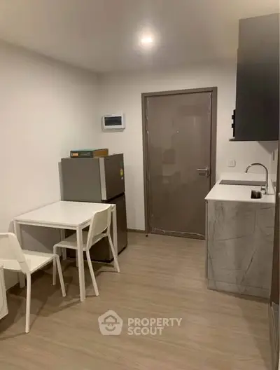 Modern compact kitchen with sleek design and dining area in cozy apartment.