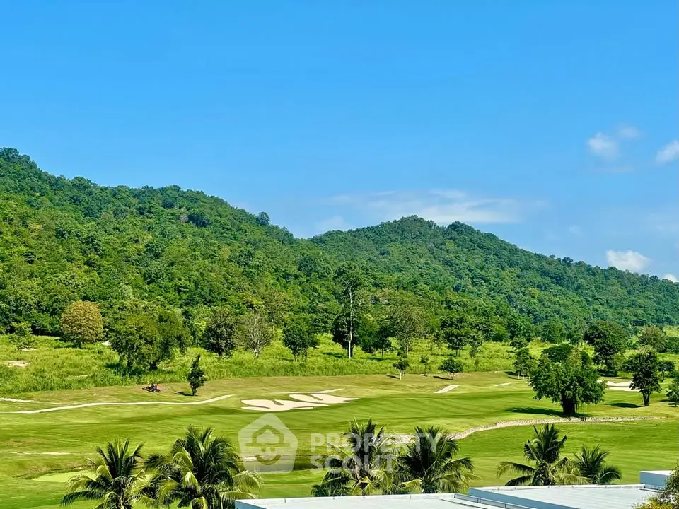 Scenic golf course view with lush greenery and rolling hills under a clear blue sky.