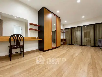 Spacious modern bedroom with wooden flooring and large wardrobe in a stylish apartment.
