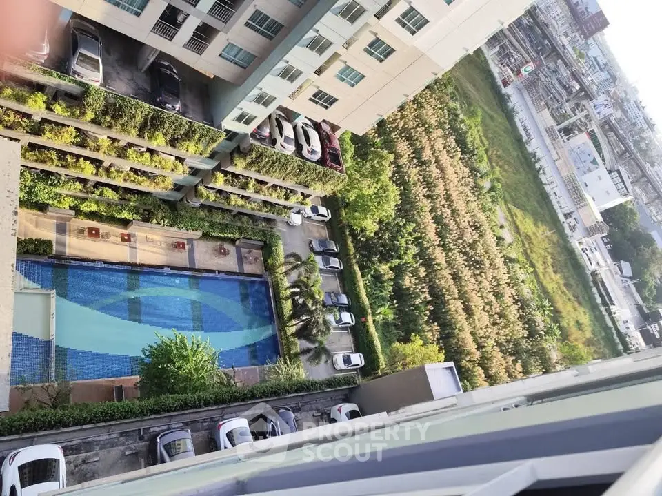 High-rise building with pool and parking view from above, showcasing urban living amenities.