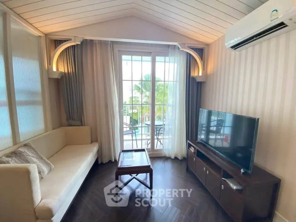 Charming living room with elegant decor and balcony view, featuring cozy seating and modern entertainment setup.