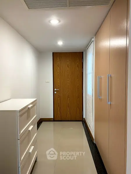 Modern hallway with sleek storage and wooden door in minimalist design.