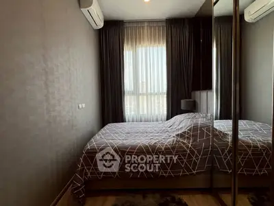 Cozy bedroom with modern decor and large window offering natural light.