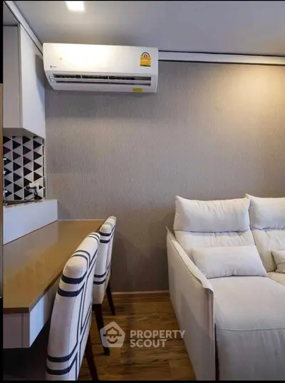 Modern living room with stylish sofa and air conditioning unit, featuring elegant decor and cozy ambiance.