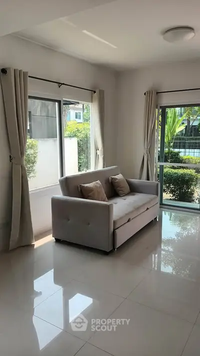 Bright living room with modern sofa and large windows overlooking garden.