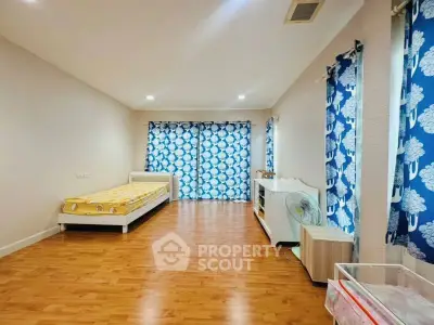 Spacious bedroom with wooden flooring and vibrant blue curtains