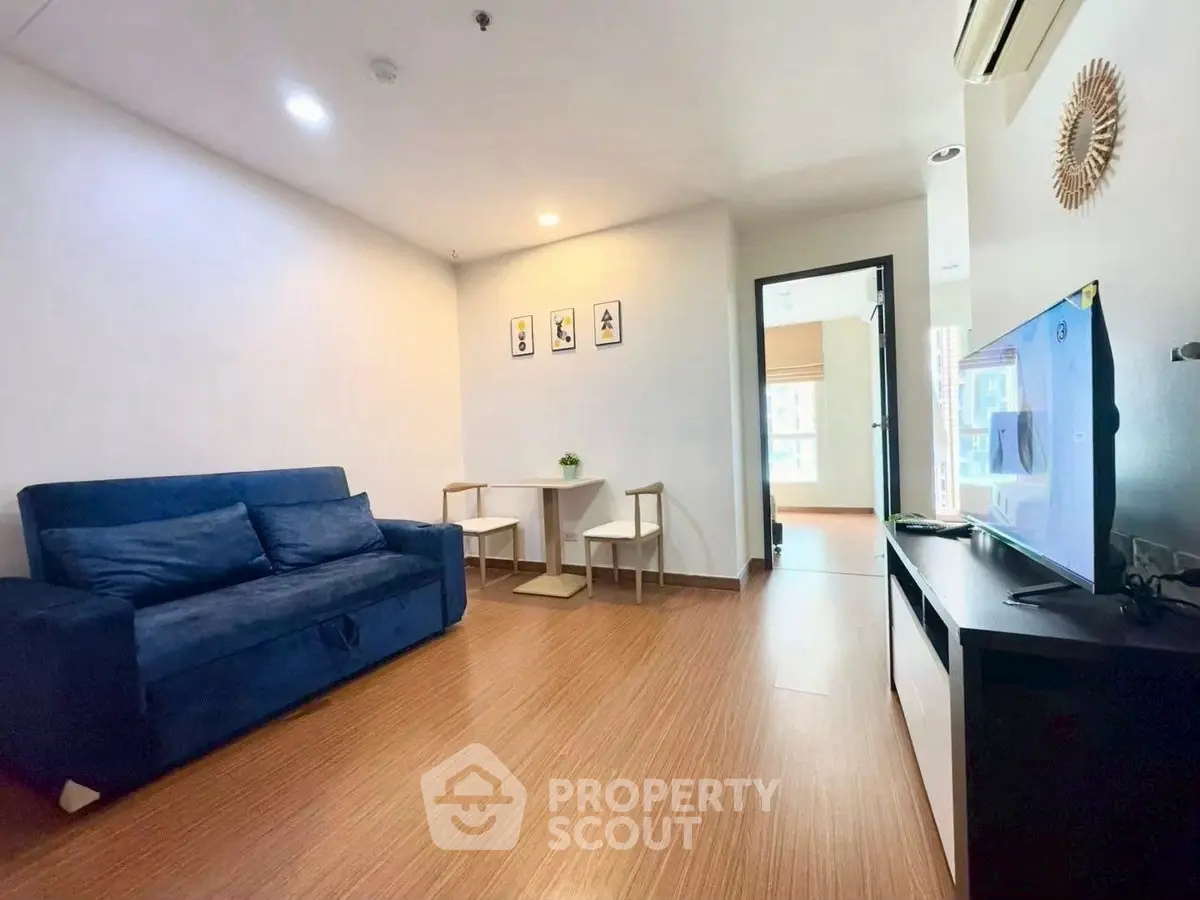 Modern living room with blue sofa and wall-mounted TV in a stylish apartment.