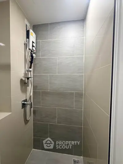 Modern bathroom with sleek gray tiles and a wall-mounted shower unit.