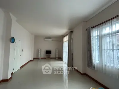 Spacious living room with large windows and modern decor, perfect for family gatherings.