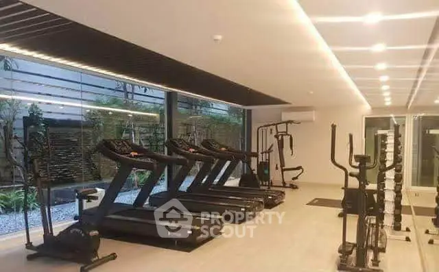 Modern gym with state-of-the-art equipment and large windows offering garden views.