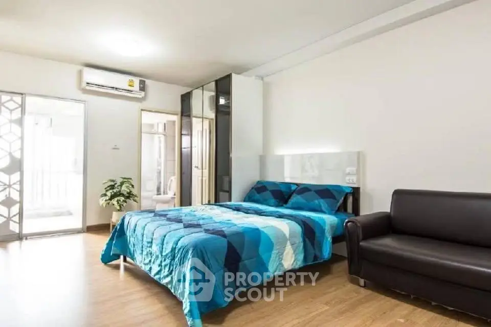 Spacious modern bedroom with stylish decor and cozy seating area.