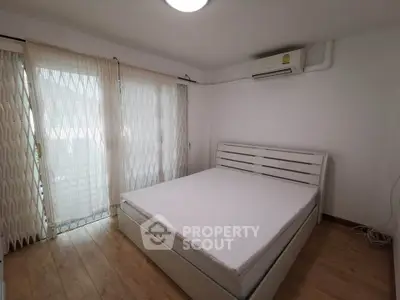 Spacious bedroom with large windows and modern air conditioning unit