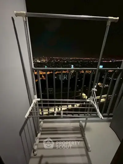 Stunning night cityscape view from a high-rise balcony with drying rack.