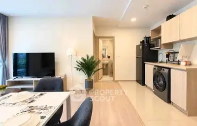 Modern open-plan living room with kitchen and dining area, featuring sleek appliances and stylish decor.