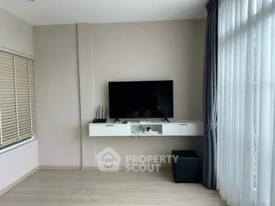 Modern living room with sleek TV setup and large window with curtains