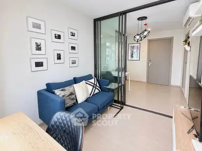Modern living room with blue sofa, glass partition, and stylish decor in a bright apartment.