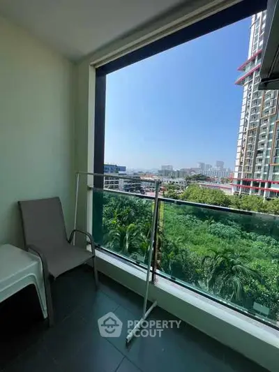 Spacious balcony with stunning city view and lush greenery, perfect for relaxation.