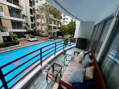 Spacious balcony overlooking a serene pool in a modern apartment complex.