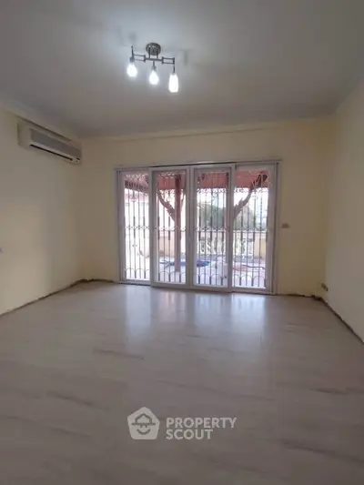 Spacious living room with large windows and modern lighting, ideal for natural light and comfort.