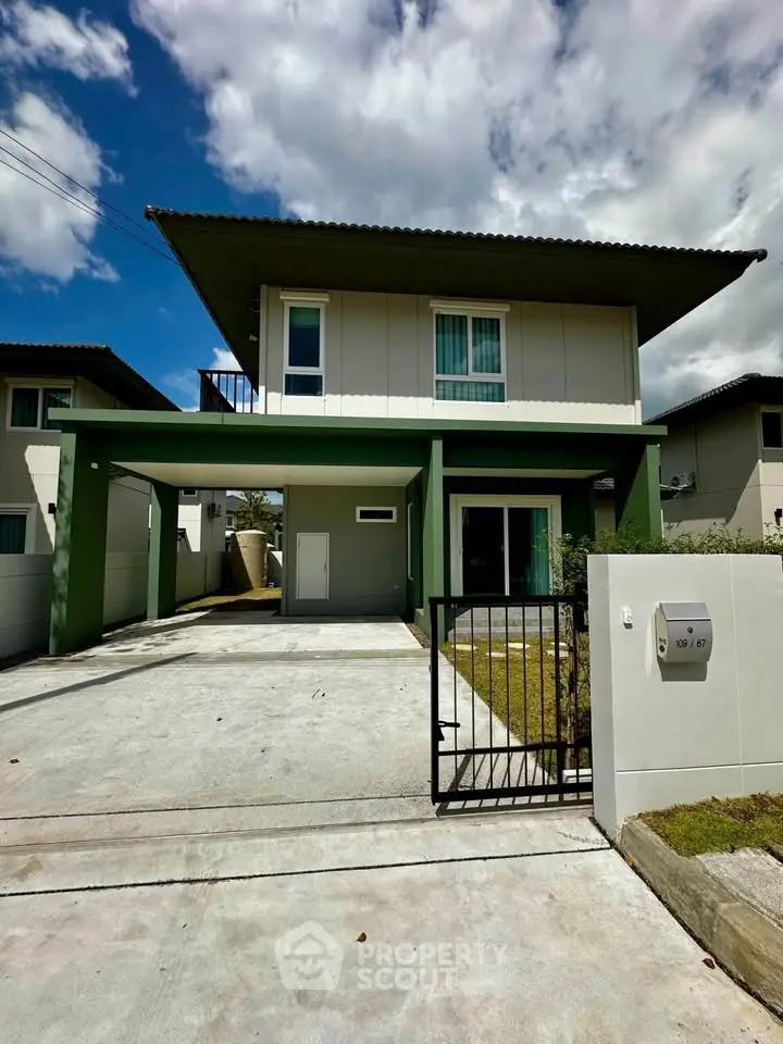 Modern two-story house with green accents and spacious driveway under a clear blue sky.