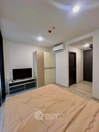 Modern bedroom with cozy bed, TV, and air conditioning in stylish apartment.