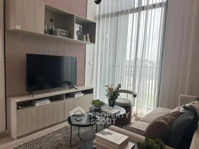 Modern living room with stylish decor and large TV, featuring floor-to-ceiling windows.