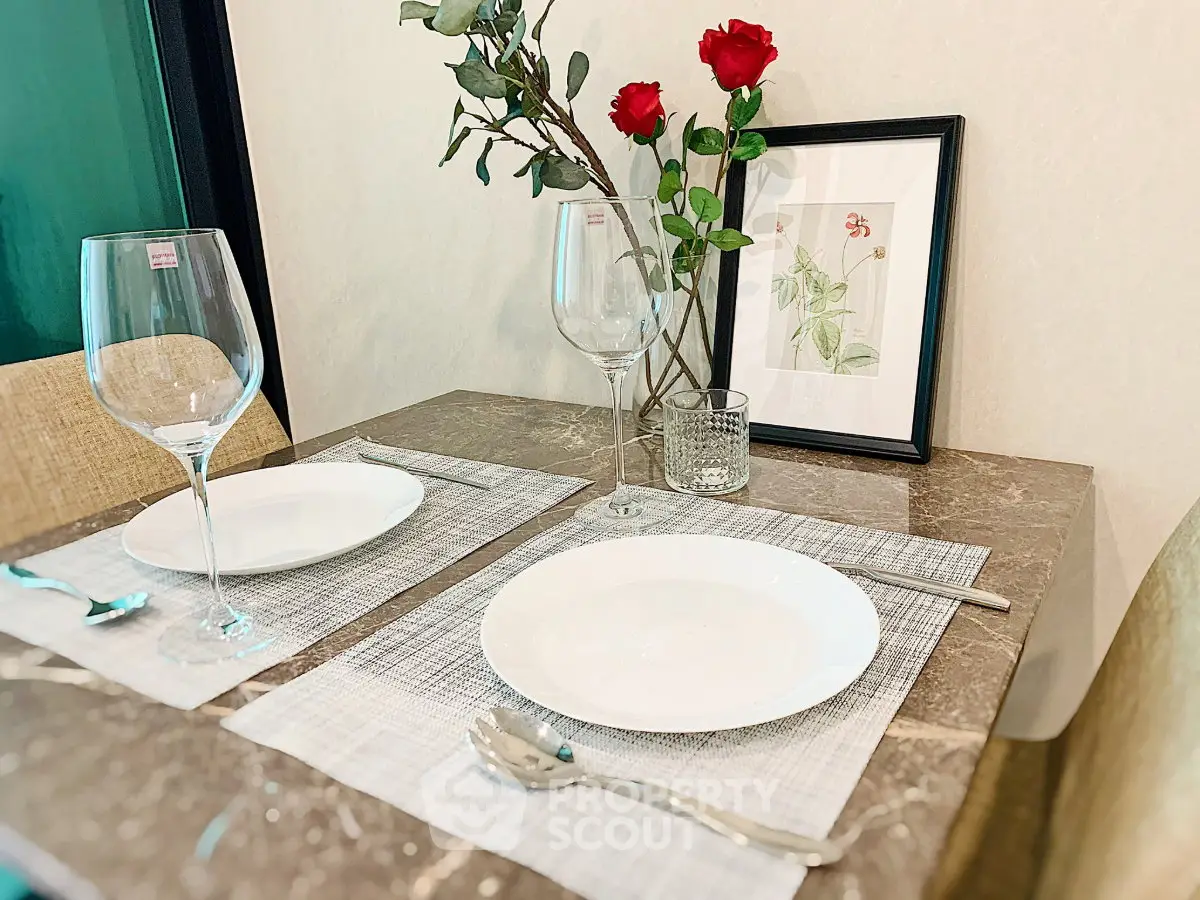 Elegant dining setup with marble table, wine glasses, and red roses in a modern home.