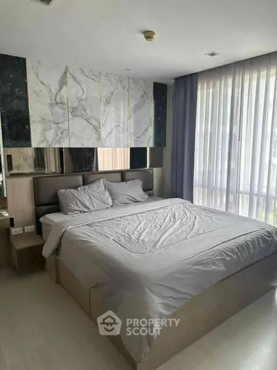 Modern bedroom with stylish marble accent wall and large windows for natural light.