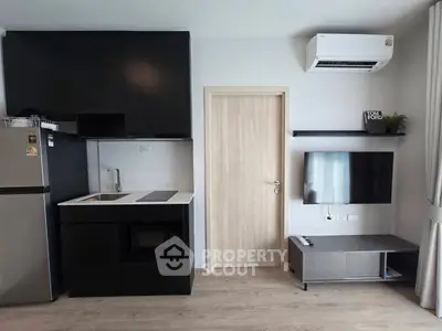 Modern compact kitchen with sleek black cabinets and integrated appliances in a stylish apartment.