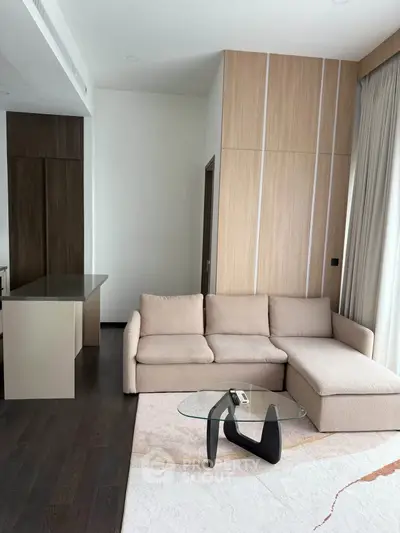 Modern living room with beige sectional sofa and glass coffee table, featuring sleek wooden accents and natural light.