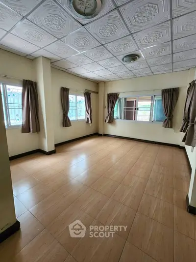 Spacious empty room with large windows and tiled ceiling, perfect for customization.