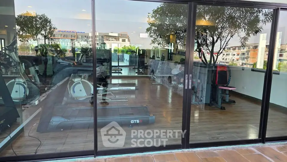 Modern gym with large windows and fitness equipment in a residential building.