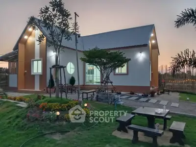 Charming countryside home with lush garden and outdoor seating area at sunset.