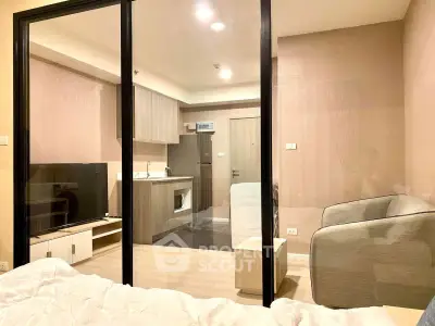 Modern studio apartment with glass partition, cozy living area, and compact kitchen.