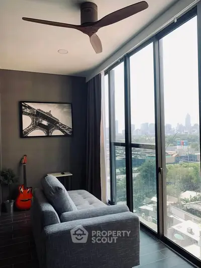 Modern living room with large windows and city view, featuring a stylish sofa and guitar decor.