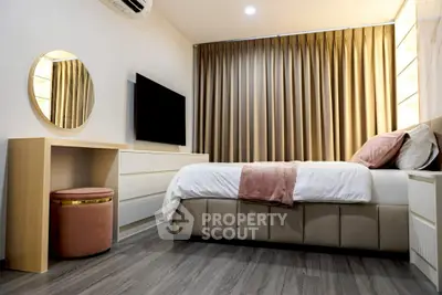 Modern bedroom with stylish decor, featuring a cozy bed, elegant curtains, and a wall-mounted TV.