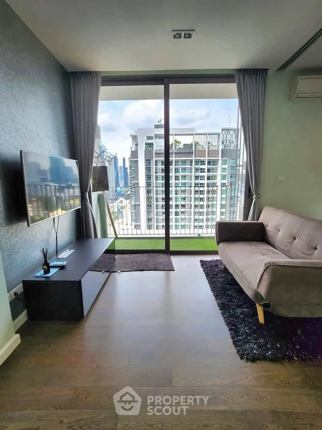 Modern living room with city view, featuring sleek furniture and floor-to-ceiling windows.