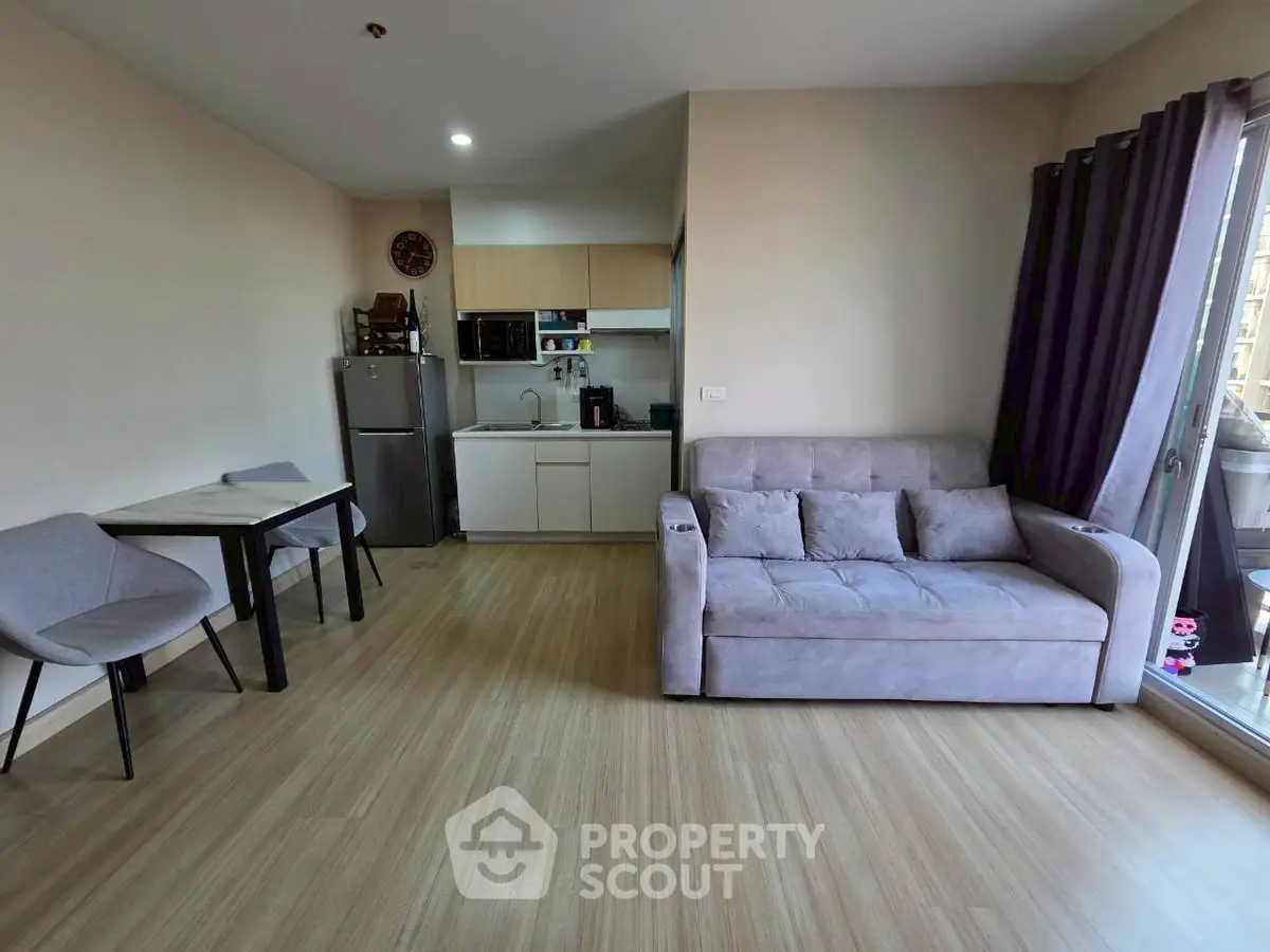 Modern living room with cozy sofa and compact kitchen in open layout apartment.